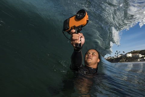 photographer with iPhone 7 water housing and pistol grip taking a picture of a curling wave