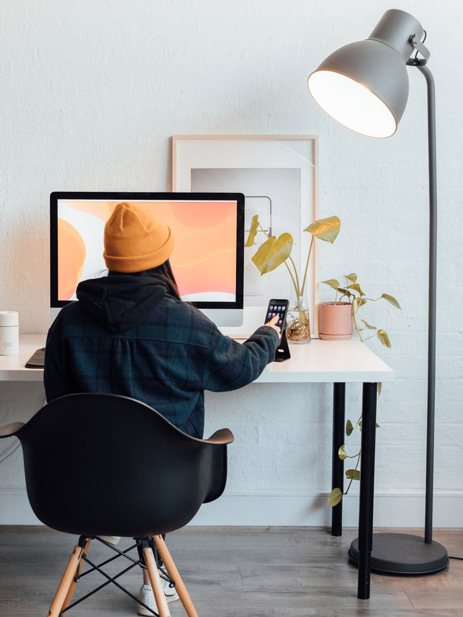 photo of person sitting at their desk using phone on desk mount