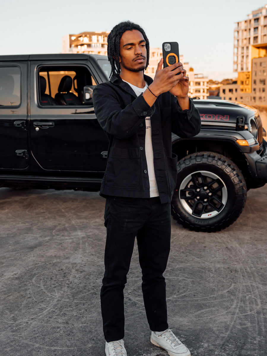 Person standing by car taking a photo with their iPhone in Quad Lock MAG Case and Orange MAG ring